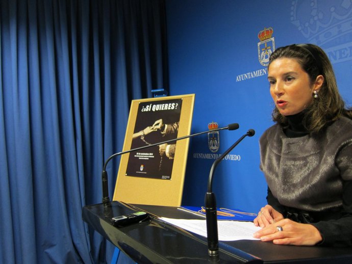 La Concejala Silvia Junco, Muestra El Cartel Conmemorativo Del 25 De Noviembre.