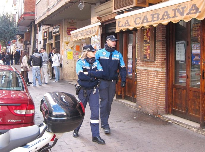 Agentes Municipales Patrullan A Pie En La Calle Paraíso, Con Jóvenes Al Fondo
