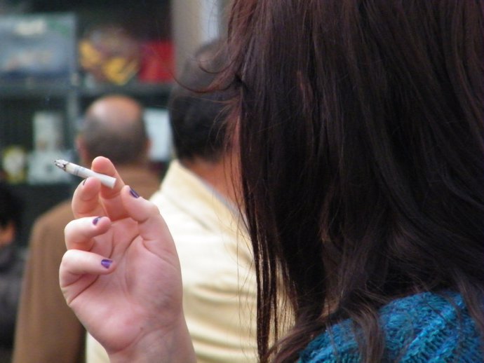 Una joven fumando un cirgarro en una terraza