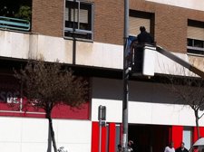 Un Operario Retira Una Banderola Del PP Junto A La Sede Del PSOE