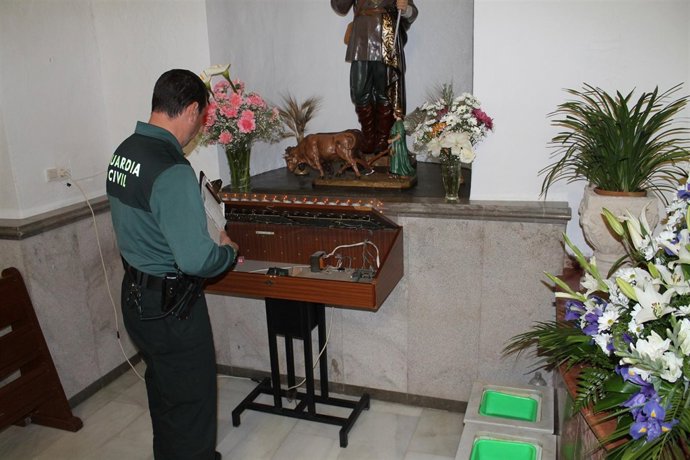 Un Agente Examina Un Lampadario En Una De Las Iglesias Que Sufrieron Robos.