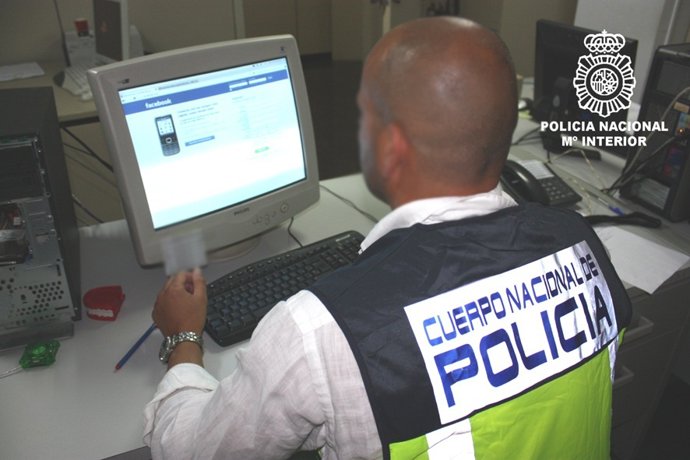 Un Agente De La  Policía Nacional Investiga Una Estafa En La Red