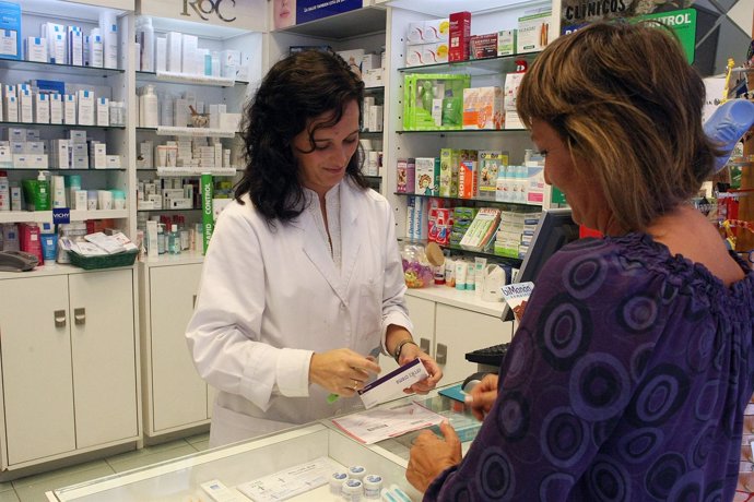 Una farmacéutica atiende en su botica a una usuaria