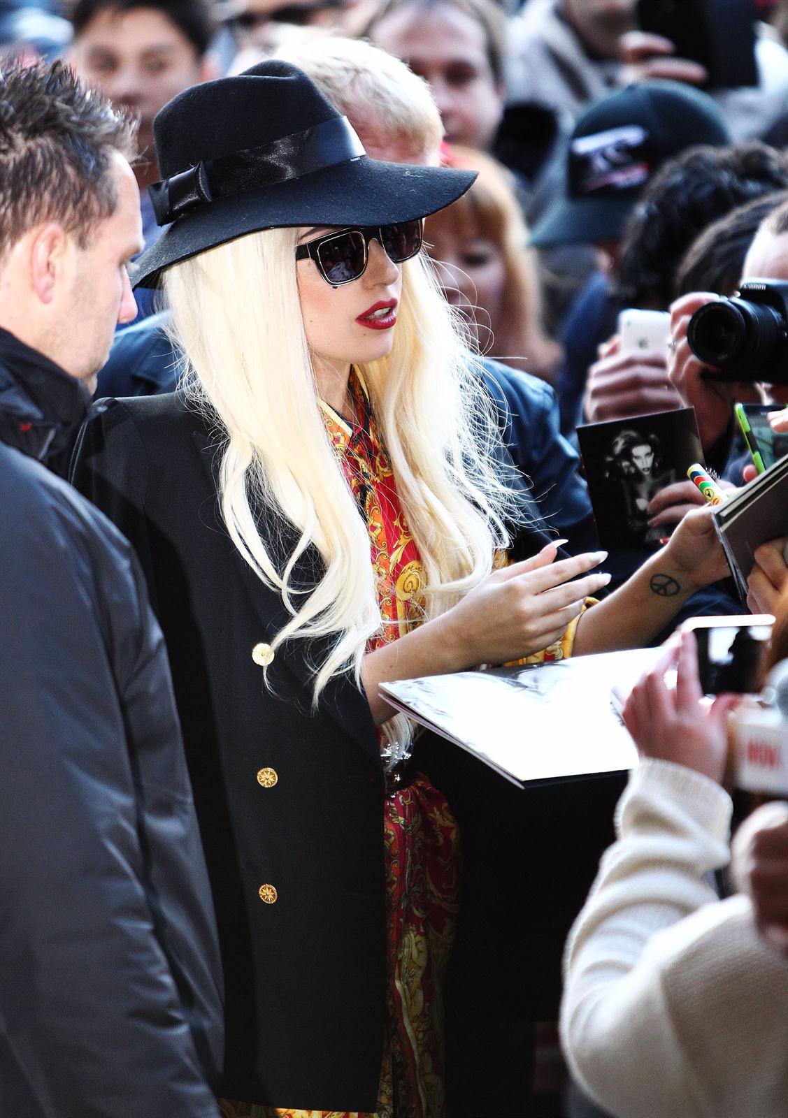 Lady Gaga firma autógrafos a sus fans en la entrada de un concierto.