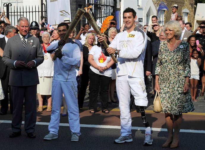 Olympic torch bearer Jay Kamiraz (2nd L) hands over to torch bearer Scott Moorho