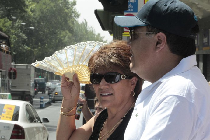 Un matrimonio se protege del sol con abanico y gorra