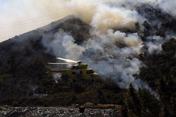 Helicóptero de extinción tras recoger agua en el río Sil, al fondo uno de los fo