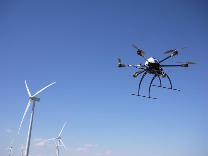 Un aracnocóptero sobrevolando un parque eólico.