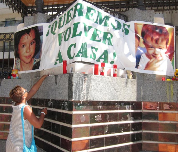 Una mujer deposita una vela debajo de la pancarta por Ruth y José. 