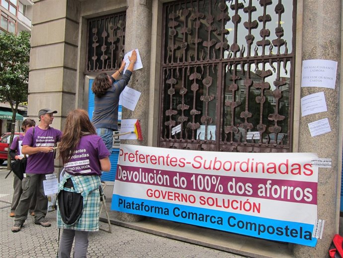 Afectados por preferentes pegan carteles en una oficina de Novagalicia Banco