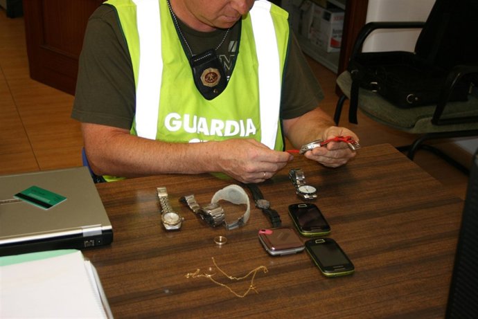 Un Agente Revisa Algunos Objetos Recuperados Tras Detener A Autores De Robos.