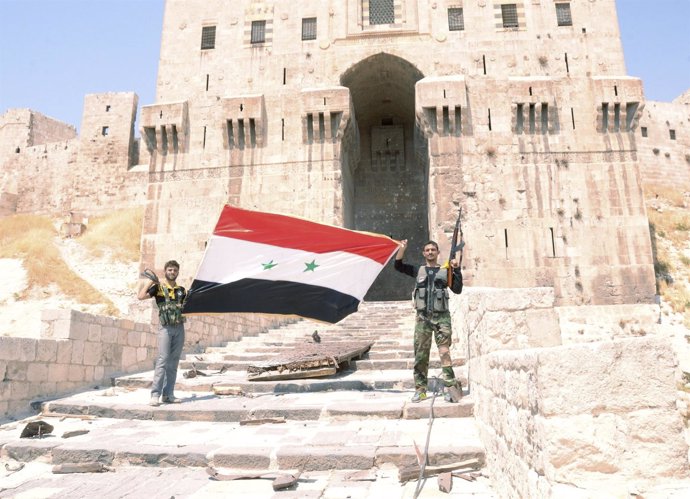 Soldados del gobierno sirio ondean la bandera nacional en Alepo