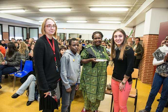 Dos alumnos y una profesora del centro entregan unos obsequios a Mama Tunza. 