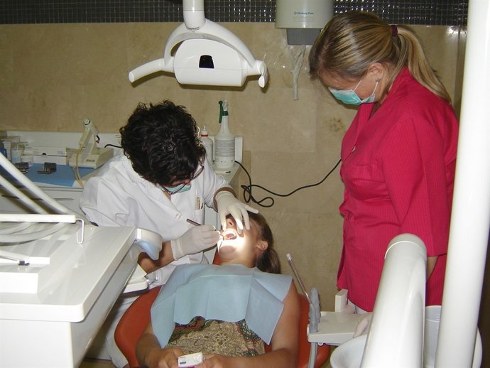 Una médico dentista revisa la boca de una paciente