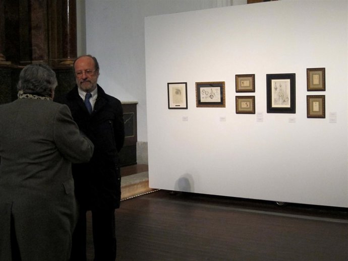 León de la Riva conversa con un comisario de la exposición pictórica