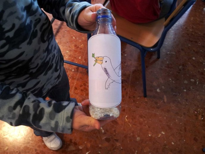 Un niño con una botella reciclada como isntrumento musical