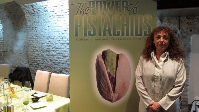 Imagen de la doctora Palacios junto a un cartel de la American Pistachio Growers