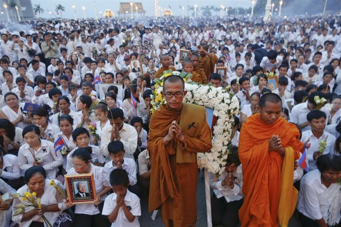 Thousands of mourners pray at the gates of the Royal Palace after the coffin of 