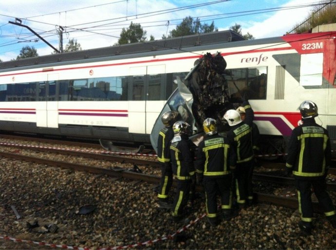 Bomberos retirando coche de la vía del tren