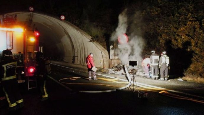 Bomberos y policías forales junto al vehículo siniestrado. 
