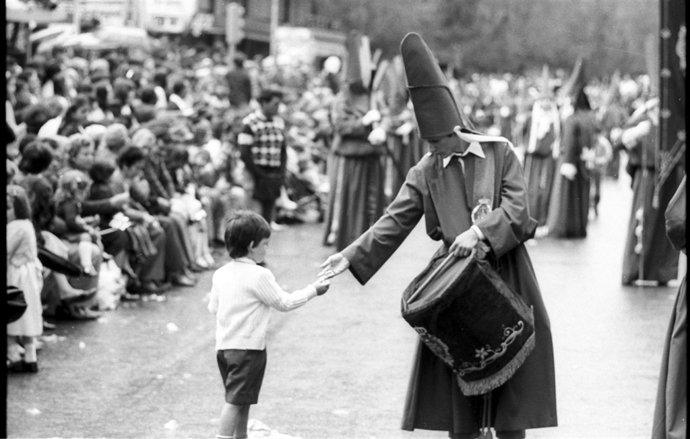 Un nazareno ofrece un caramelo a un niño. Fotografía de Juan Orenes 