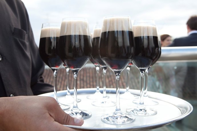 Una bandeja con copas de cerveza negra