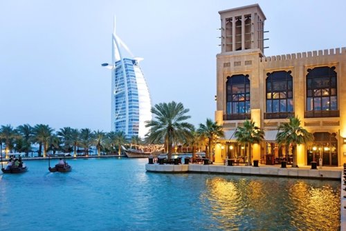View of boats sailing in river by Madinat Jumeirah Hotel with Burj Al Hotel in t