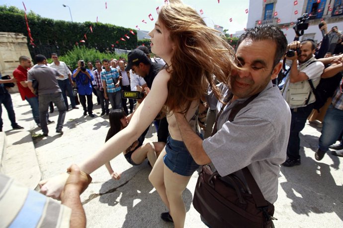 Police officers detain a FEMEN activist during a protest against the arrest of t