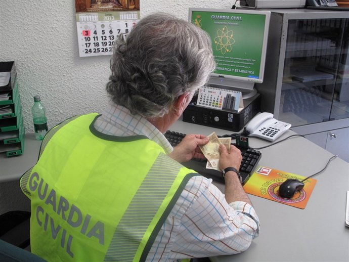 Un agente de la Guardia Civil sostiene varios billetes falsos.
