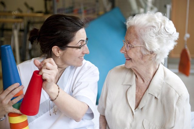 Imagen de una profesional sanitaria de Sanitas junto a una paciente