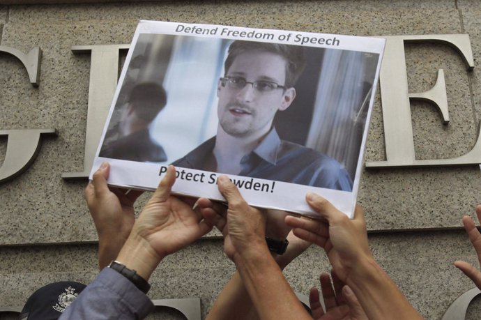 Manifestantes con una foto de Edward Snowden
