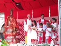 Los niños honran a San Fermín y lo rodean de flores rojas y blancas