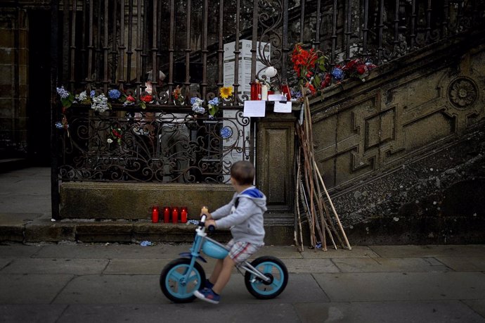 Un niño pasa en bicicleta por el frente de la Catedral de Santiago de Compostela