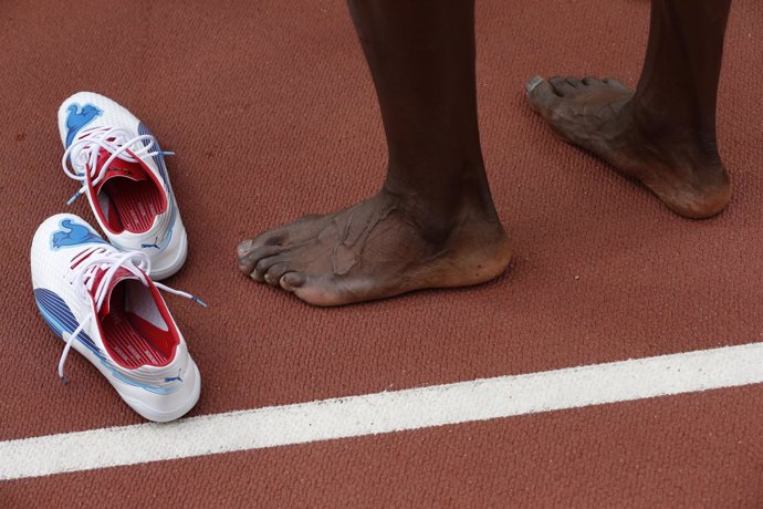 El jamaiquino Usain Bolt se saca los zapatos luego de ganar la carrera de relevo