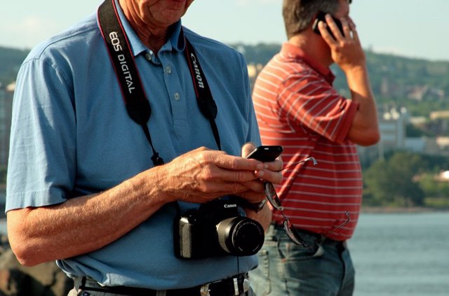 Turista en la playa con cámara y teléfono móvil smartphone verano vacaciones