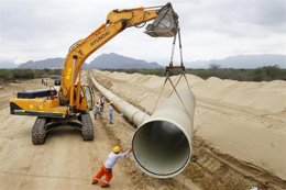 Un trabajador ayuda a colocar una parte de un ducto durante la construcción de u