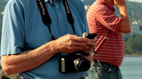 Turista en la playa con cámara y teléfono móvil smartphone verano vacaciones