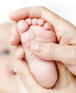 Un profesional sanitario sostiene el pie de un bebé.