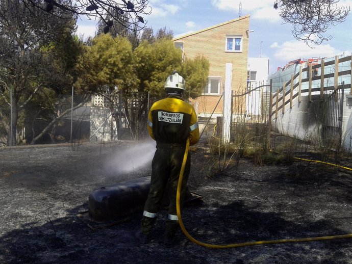 Un bombero trabaja en la extinción del incendio cerca de una casa