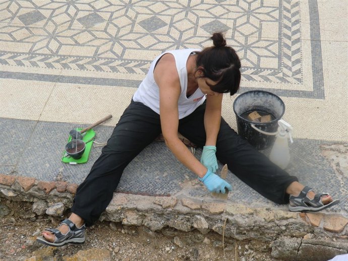 Una técnica restaura uno de los mosaicos de las ruinas de Empúries.