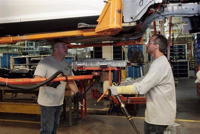 Trabajadores de una planta de Ford instalan un cargador de baterías 