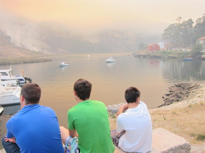 Tres jóvenes observan como el fuego se aproxima a O Ézaro (Dumbría)