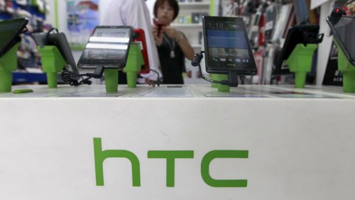 Un grupo de clientes observan unos teléfonos de la firma HTC en una tienda de Ta