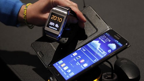Un periodisa observa el reloj Galaxy Gear de Samsung junto a un teléfono Galaxy 