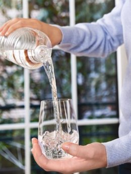 Imagen de un hombre sirviéndose un vaso de agua
