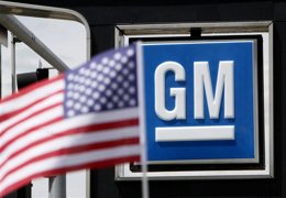 Una bandera de Estados Unidos detrás de un logo de General Motors en una concesi