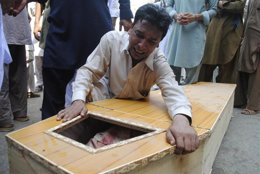 Un hombre cristiano llora sobre el ataúd de un familiar asesinado en un doble at