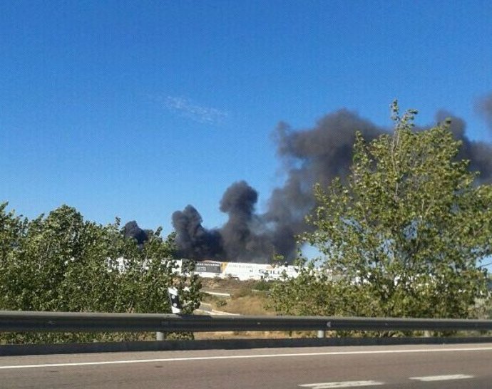 Columna de humo de la fábrica de Paterna incendiada desde una carretera