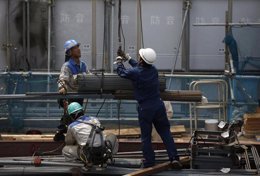 Trabajadores cargan planchas de acero en una obra en construcción en Tokio. Agos