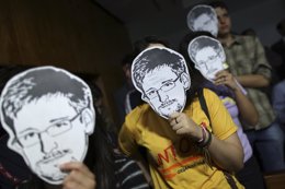 Personas utilizando máscaras con el rostro de Edward Snowden.